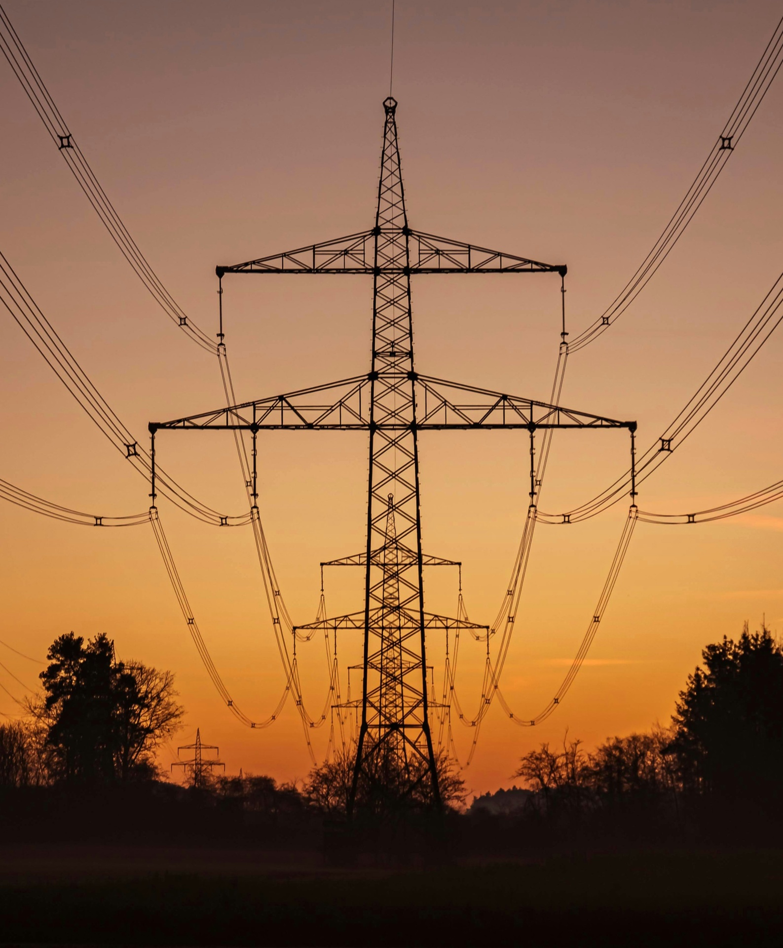 Transmission tower silhouetted against a sunset sky